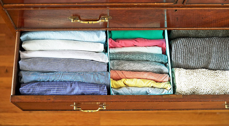 Set of wooden drawers open with shirts and jumpers
