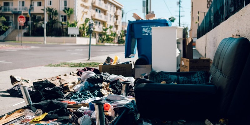 Illegally dumped rubbish, including an old couch dumped on an urban street.