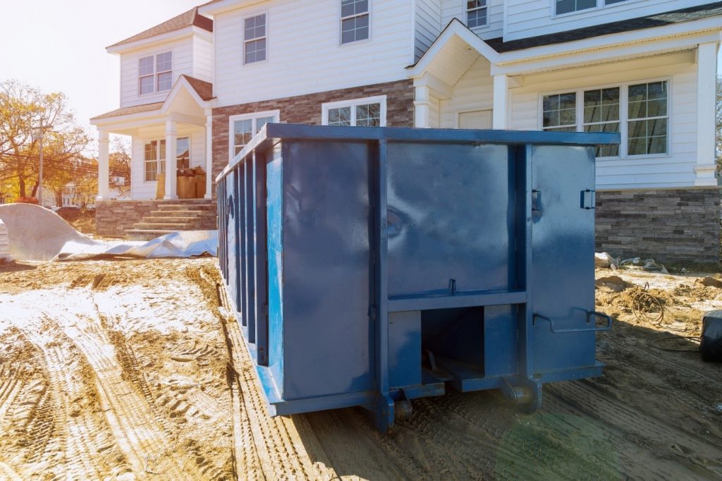 Large blue skip bin outside white house under construction