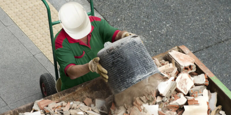 man-loading-building-rubble-into-skip-bin