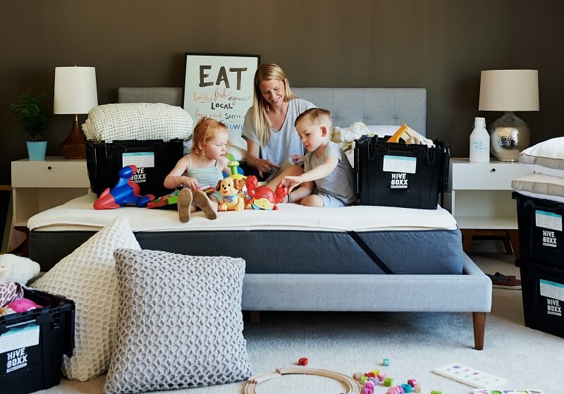 woman and two young children on a bed playing with toys