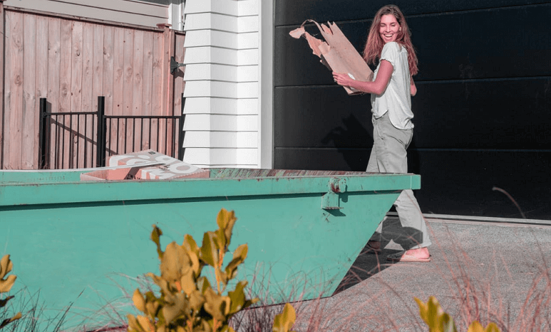 woman loading rubbish into a skip bin